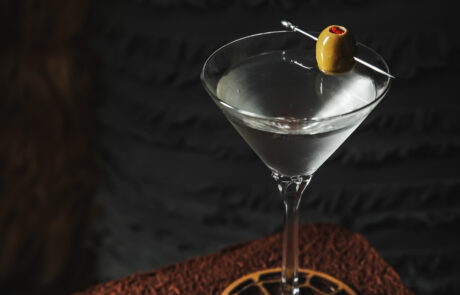 Martini with olive balanced on rim with silver toothpick