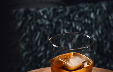 Bourbon cocktail with moody lighting. Big ice cue in square glass