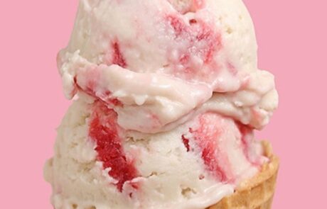 Strawberry ice cream in waffle cone with pink background